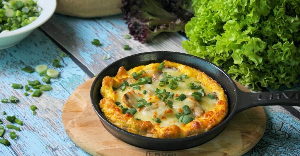 Tasty frittata in a skillet with fresh greens on a rustic wooden table, perfect for a hearty breakfast.